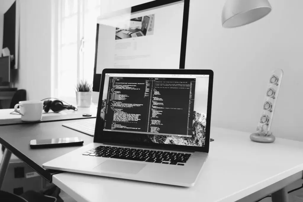 Arbeitsplatz mit Laptop und Quellcode